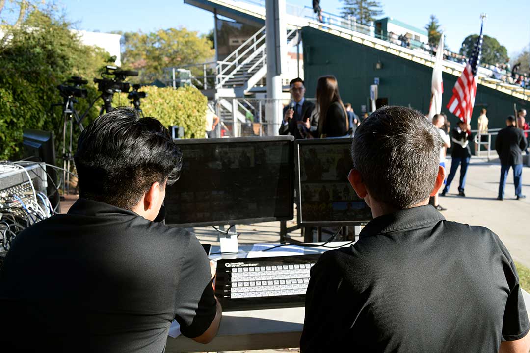Morales and Martinez watch from the control table as Truong and Sydney prepare to bring Walsh on air. Alex G. Spanos Stadium, San Luis Obispo, CA. Oct. 26.