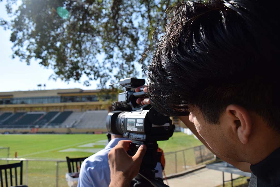 Journalism junior Francisco Martinez assists in setting up the Mustang Gameday set by locking in a JVC camera to a tripod. Alex G. Spanos Stadium, San Luis Obispo, CA. Oct. 26.