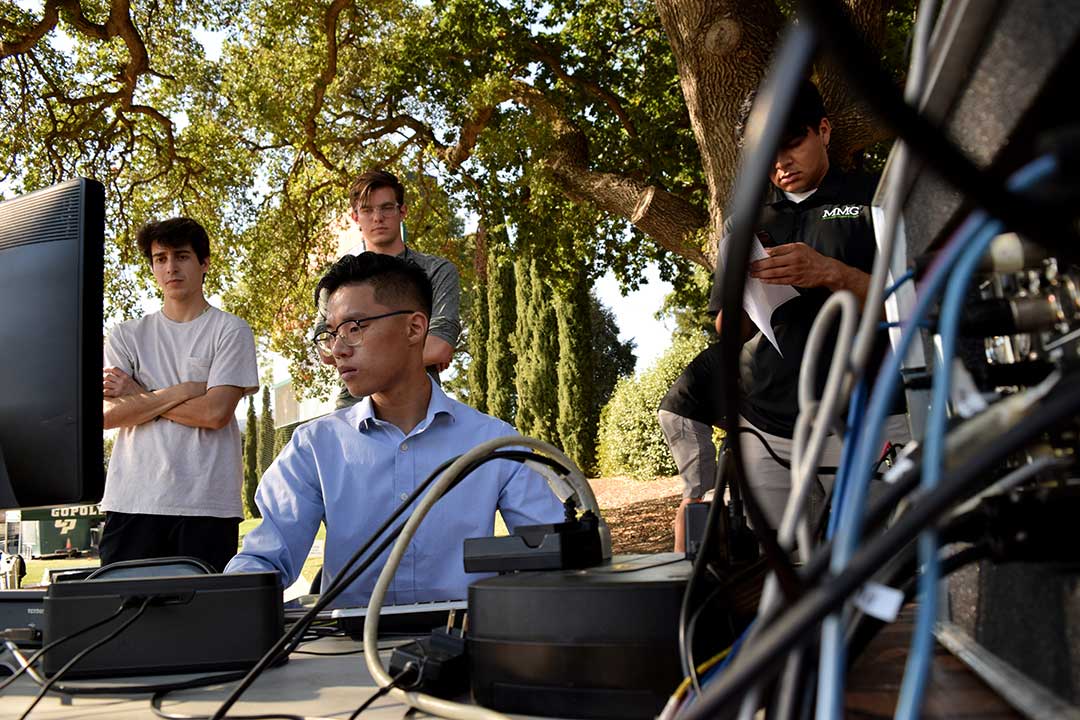 Truong puts the finishing touches on the show's rundown as journalism sophomore Mathew Bornhorst and journalism junior Tony Farias watch from behind. Bornhorst and Farias aid in set up and camera operation for Mustang Gameday. Alex G. Spanos Stadium, San Luis Obispo, CA. Oct. 26.
